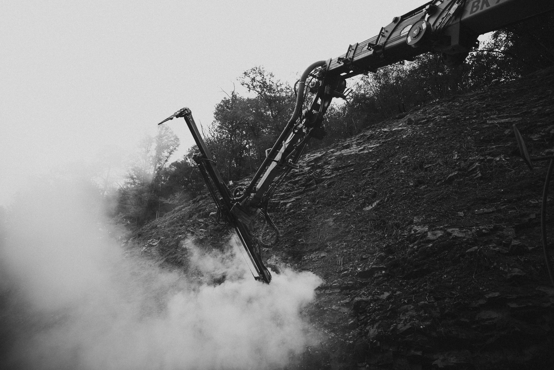 Maschine zur Felssicherung in Nutzung, umgeben von Staubwolken